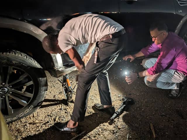 Bishop Jonathan Frost holds a torch as his colleague changes the tyre of their car in Ghana earlier this year