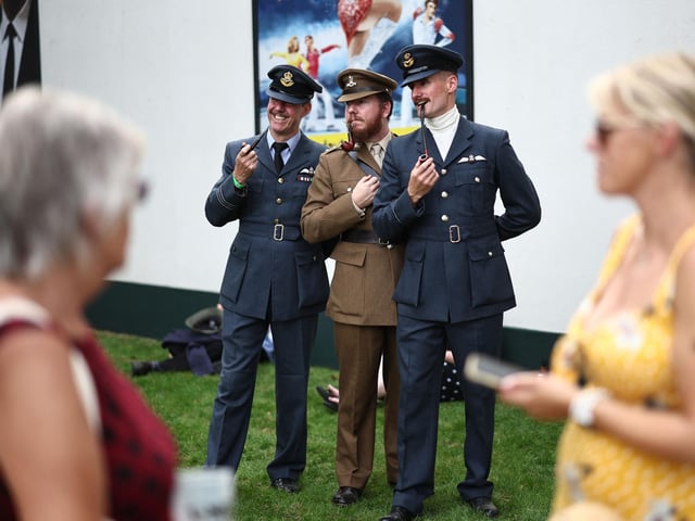 People wearing period clothing attend the opening day of Goodwood Revival at the Goodwood Motor Circuit in Chichester on September 8, 2023. The only historic motor race meeting to be staged entirely in a period theme, Goodwood Revival is an immersive celebration of iconic cars and fashion. (Photo by HENRY NICHOLLS / AFP) (Photo by HENRY NICHOLLS/AFP via Getty Images)