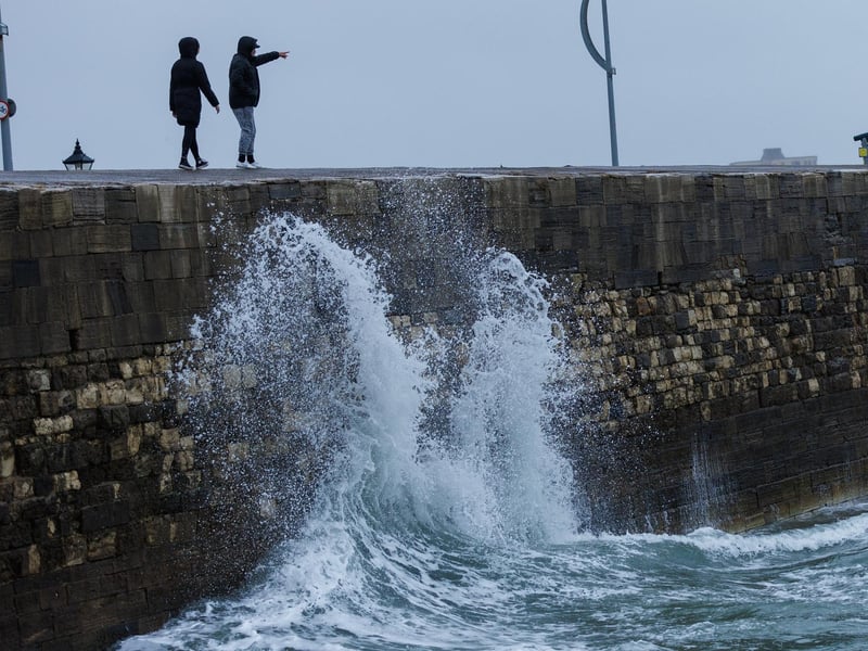 The stormy sea at high tide crashed waves onto footpaths as passer-by's did their best to get out the way