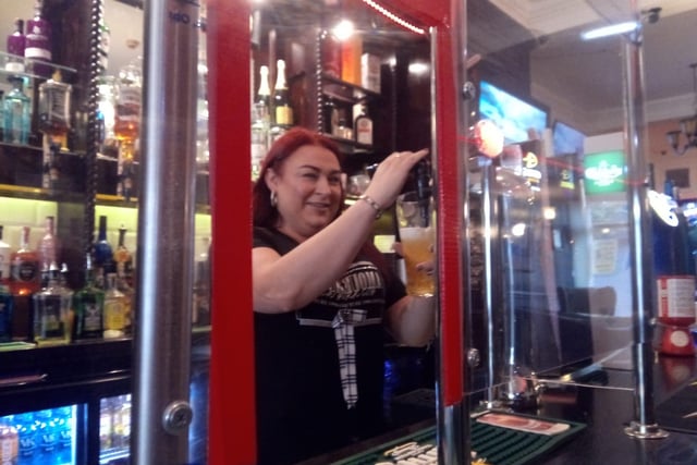 A member of staff at The Blandford in Sunderland behind a safety screen.