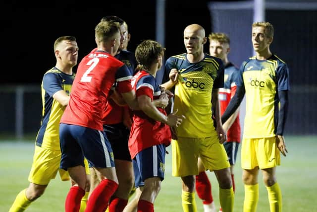 Harry Birmingham (middle of the three Moneyfields players in yellow) was sent off at New Milton during a shock Wessex League Cup exit. Picture by Dave Bodymore.