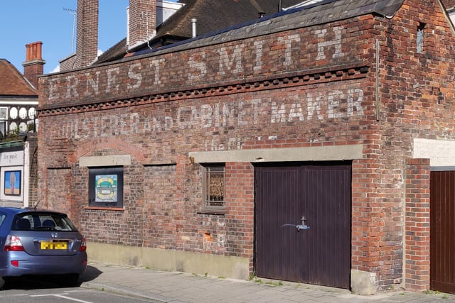 This sign by the Barley Mow pub reads: 'Ernest Smith, Upholsterer and Cabinet Maker'. Mr Smith's name is also on the clocktower above Tony Wood Hairdressing in Castle Road.