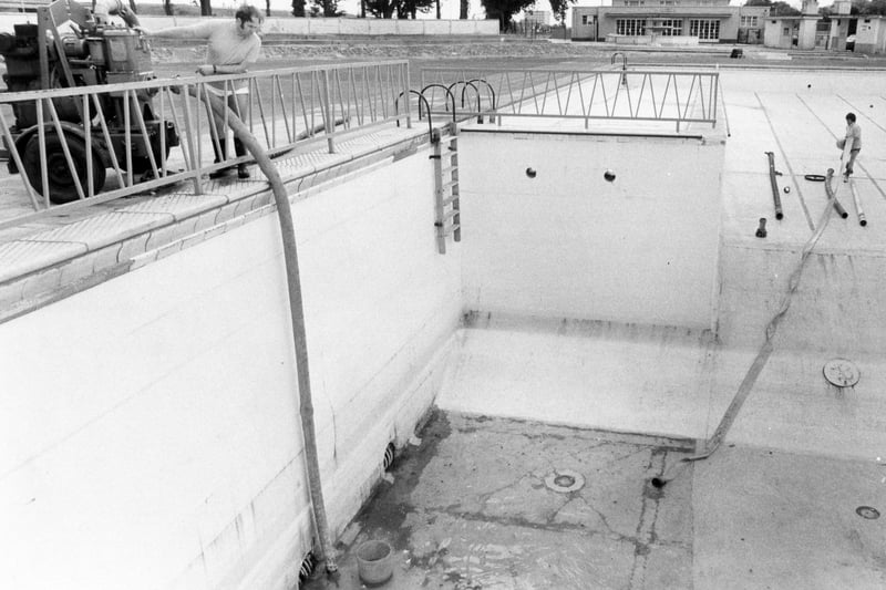 Hilsea Lido pool supervisor Mr N Padmore, left, and at the base of the pool, assistant N Goddard pumping out the dirty rainwater ready for refilling in June 1981. The News PP1282