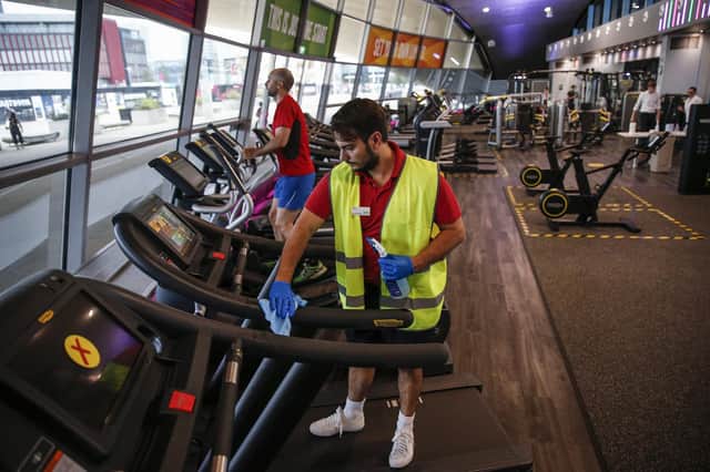 Disinfecting a treadmill in a gym, which was allowed a reopen over a fortnight ago. Photo by Hollie Adams/Getty Images.