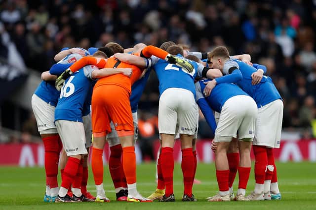 Pompey players in a huddle after their brave Spurs display. (Photo by IAN KINGTON/AFP via Getty Images)
