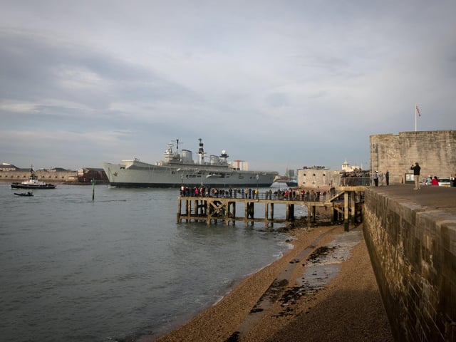 People watching as Britain's last serving aircraft carrier HMS Illustrious is towed from her home port at Portsmouth after being sold for scrap on December 7, 2016 in Portsmouth. Photo by Matt Cardy/Getty Images