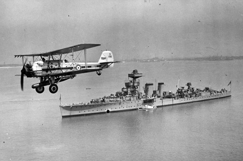 October 1938:  A torpedo-bomber from the RAF training school at Gosport flying over HMS Coventry in the Solent.  (Photo by Central Press/Getty Images)