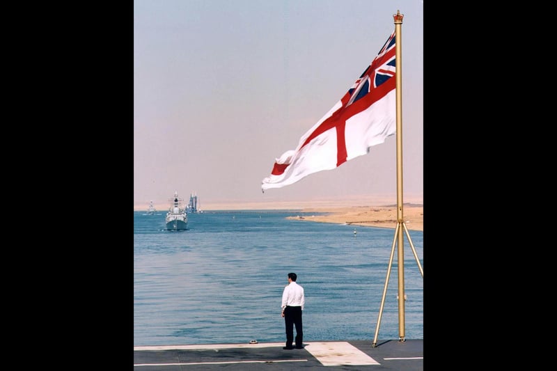 HMS Illustrious passage through the Suez Canal on 3 February 2000. Tom Harrison watches HMS Gloucester (Foreground) and HMS Monmouth transit through the Suez Canal from the flight deck of HMS Illustrious. The Royal Navy aircraft carrier and her task group transitted Suez en route for the Arabian Gulf where she will participate in a series of exercises and visits with Arab nations, including patrolling the no fly zone over southern Iraq with her embarked Sea Harrier fighter aircraft.PA handout Photo/Courtesy of Royal Navy