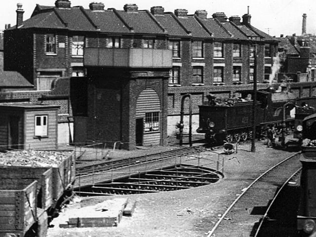 Water tower and turntable at Portsmouth and Southsea Railway

Another feature of the railway line into Portsmouth now long gone was the engine turntable. In Portsmouth there were at one time three of these. One outside the Harbour station on the up side, this one outside the low level Town station and the other in the roundhouse at Fratton depot.
This view was taken from Jacob's ladder footbridge and to the rear can be seen  houses in Canal Walk. Later the new signal box was built on the site and even this is now redundant as the new signalling centre at Havant as since been commissioned.