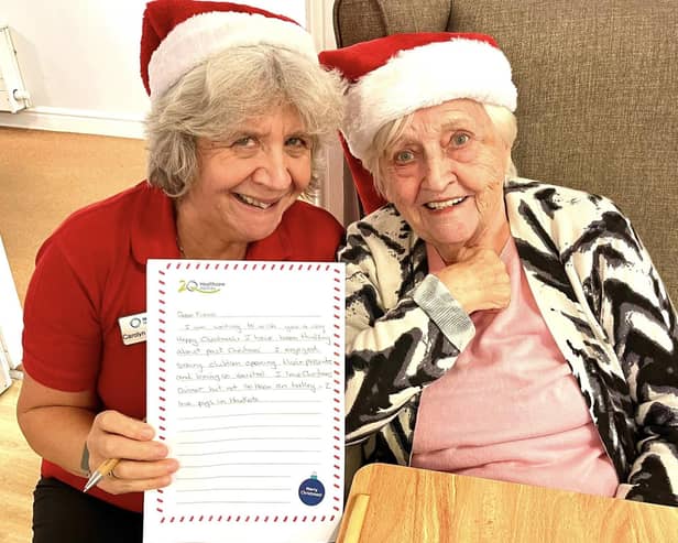 A resident and team member share a heartfelt moment while reading a Christmas letter