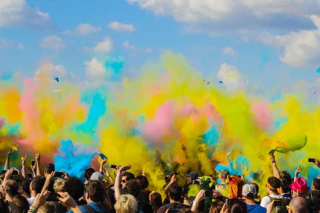 A crowd of people throwing powdered colour paint in the air