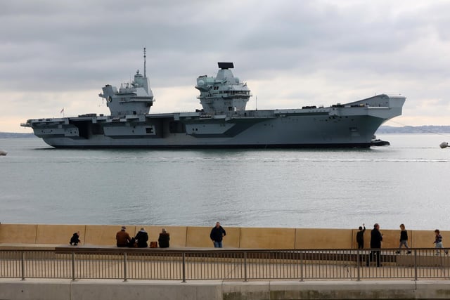 HMS Queen Elizabeth passes the newly reopened walkway on the sea defences at Long Curtain Moat, as she returns to Portsmouth Naval Base