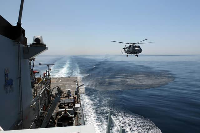 A Wildcat helicopter flies next to HMS Trent in the Mediterranean