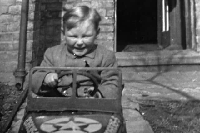 Hugh as a five-year-old in a toy military vehicle at his Portsmouth home.