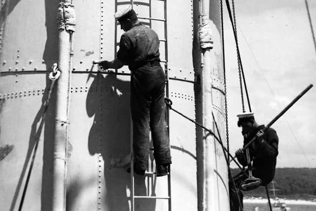 A laborious job from the past: Members of HMS Sussex's company on paint shop duties, probably in the 1930s. Picture: Andrew August collection.