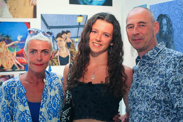 Art scholar Tabby proudly displays her work accompanied by her parents