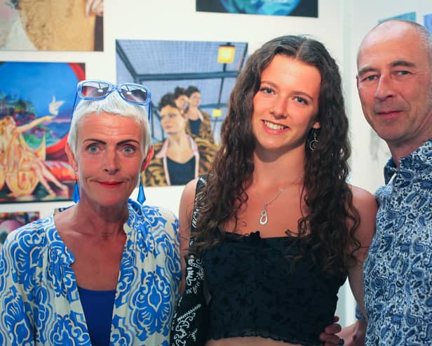Art scholar Tabby proudly displays her work accompanied by her parents