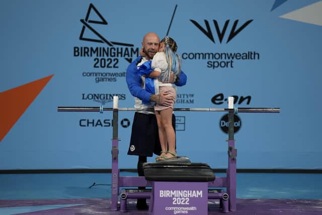 Micky Yule hugs his daughter after winning the bronze medal for the men's heavyweight para powerlifting final at the Commonwealth Games at The NEC in Birmingham. Picture: AP Photo/Aijaz Rahi