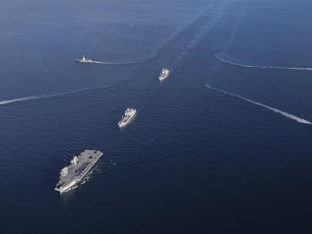 The UK Carrier Strike Group during Exercise Joint Warrior. Aerial imagery of the UKCSG Task Group taken from a Merlin Mk2 of 814 Naval Air Squadron.Viewed from the front - HMS Prince of Wales; Row 2 (L-R) – HMS Portland, RFA Tidesurge, HMCS Charlottetown; Row 3 (L-R) – SNS Cristόbal Colόn, RFA Tidespring, HMDS Niels Juel.