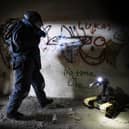 Pictured: An EOD Operator searches a building for an IED during a training exercise.