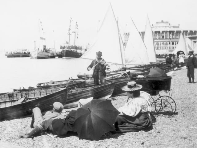 A busker scraping away on his violin on the beach near Clarence Pier, Southsea, about 1895