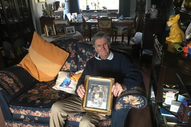 George Jeffery holding a picture of himself with his twin brother John and sister Gloria from when they were children