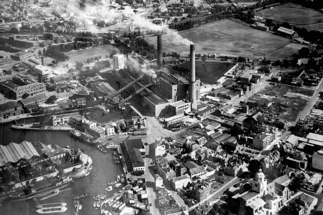 This evocative aerial photograph of Old Portsmouth dates from about 1948. To the bottom left is the Camber with the cola hoppers of Whites the coal merchant. Unloading at the wharf is a large collier with three barges alongside. At the pointed end of the coal wharves can just be seen the Bridge Tavern which is dwarfed by them. Above the Bridge Tavern is the lock for the coal barges that brought in coal for the power station. The covered travellators for taking the coal up and over Gunwharf Road can be seen. Above the lock are the buildings of HMS Vernon. To the bottom right can be seen Oyster Street which at this time passed into White Hart Lane and since these times a block of flats have been built over it. St Thomas Street passes behind the cathedral with many of the buildings just bomb sites. The bank now a residential building on the corner of Highbury Street can be Cleary seen. The east end of St Thomas's Street and Warblington Street leading into St Georges Road close by Landport Gate are both bomb sites. To the top right hand corner can be seen the United Services cricket ground where, up until the Rose Bowl was built, Hampshire played first class cricket. Above the power station chimneys the railway line from the Harbour station to Portsmouth & Southsea High Level can be seen running along its tree lined route.