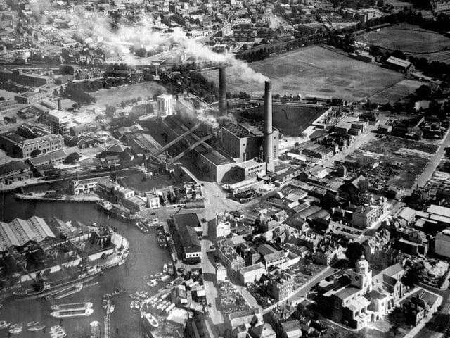 This evocative aerial photograph of Old Portsmouth dates from about 1948. To the bottom left is the Camber  with the cola hoppers of Whites the coal merchant. Unloading at the wharf is a large collier with three barges alongside. At the pointed end of the coal wharves can just be seen the Bridge Tavern which is dwarfed by them.  Above the Bridge Tavern is the lock for the coal barges that brought in coal for the power station. The covered travellators for taking the coal up and over Gunwharf Road can be seen. Above the lock are the buildings of HMS Vernon.  To the bottom right can be seen Oyster Street which at this time  passed into White Hart Lane and since these times a block of flats have been built over it. St Thomas Street passes behind the cathedral with many of the buildings just bomb sites. The bank now a residential building on the corner of Highbury Street can be Cleary seen. The east end of St Thomas's Street and Warblington Street leading into St Georges Road close by Landport Gate are both bomb sites.  To the top right hand corner can be seen the United Services cricket ground where, up until the Rose Bowl was built, Hampshire played first class cricket.   Above the power station chimneys the railway line from the Harbour station to Portsmouth & Southsea High Level can be seen running along its tree lined route.