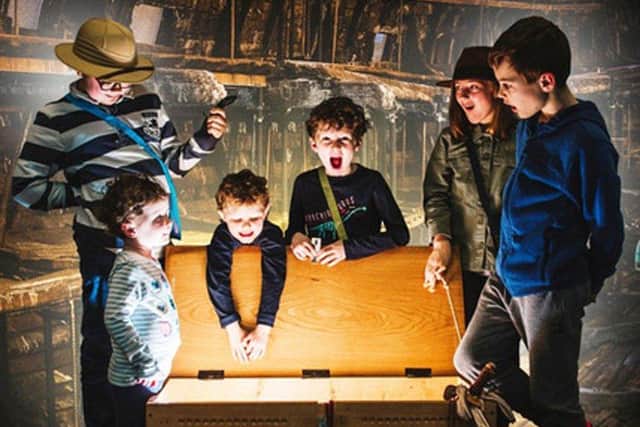 Children crowd around a chest of Tudor artefacts with the Mary Rose in the background