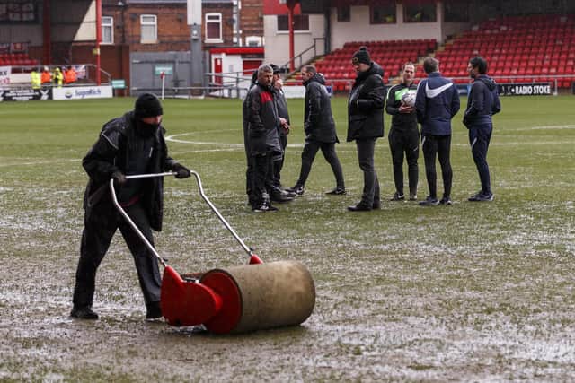 A groundsman at Gresty Road gets to work on the pitch as referee Martin Coy chats to Danny and Nicky Cowley and Crewe boss David Artell