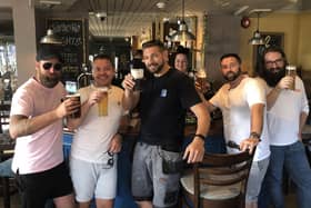 Regulars of the Greene King pub Star and Garter in Copnor Road raise a glass with landlady Meg Groves behind the bar, in July 2021.