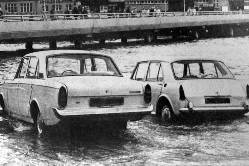 Two cars about to be overcome by the tide on the slipway at the Hard in 1970. The new approach road from the Hard to the Harbour Station can be seen in the background.
