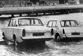 Two cars about to be overcome by the tide on the slipway at the  Hard in 1970. The new approach road from the Hard to the Harbour Station can be seen in the background.