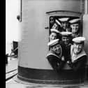 September 1928:  A group of sailors trying to squeeze out of a small door aboard the HMS Hood during naval manoeuvres.  (Photo by Fox Photos/Getty Images)