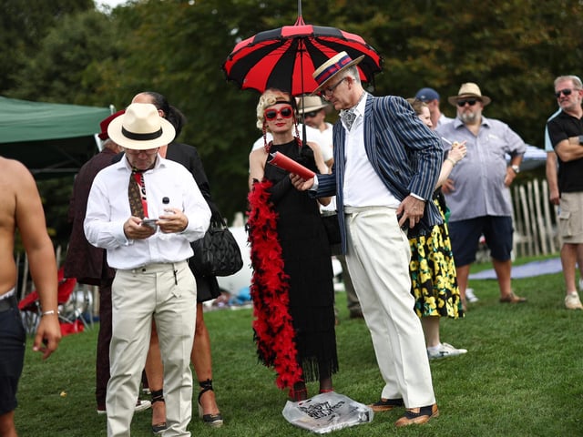 People wearing period clothing attend the opening day of Goodwood Revival at the Goodwood Motor Circuit in Chichester on September 8, 2023. The only historic motor race meeting to be staged entirely in a period theme, Goodwood Revival is an immersive celebration of iconic cars and fashion. (Photo by HENRY NICHOLLS / AFP) (Photo by HENRY NICHOLLS/AFP via Getty Images)