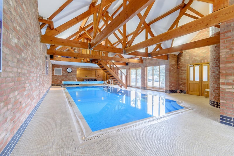 Offers over £999,950 are wanted for this eight-bedroom house which has this stunning pool complex with a gym and games room above it