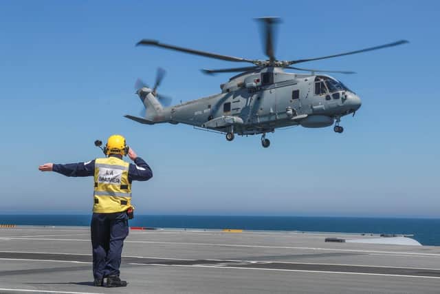 Aircraft handler directs Merlin helicopter to land on HMS Queen Elizabeth. Photo: Royal Navy