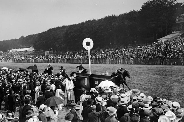 September 1909:  Spectators cheer on the riders and horses during a horse race at Goodwood.  (Photo by W. G. Phillips/Phillips/Getty Images)