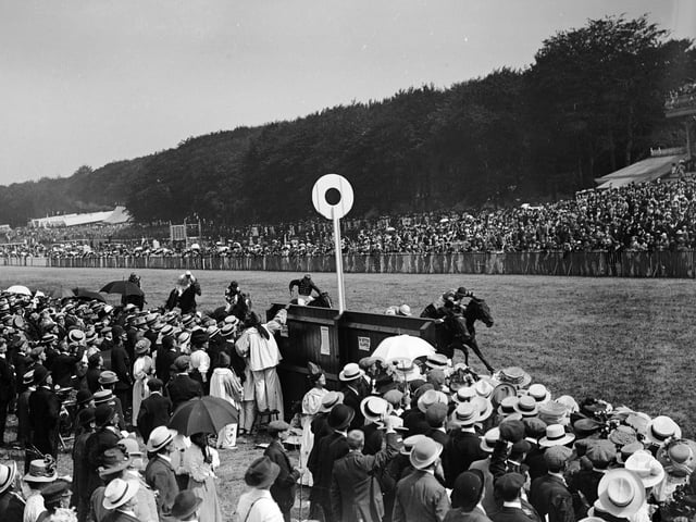September 1909:  Spectators cheer on the riders and horses during a horse race at Goodwood.  (Photo by W. G. Phillips/Phillips/Getty Images)