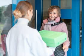 A volunteer delivering a hot meal to door of senior citizen Picture: Adobe. Posed by models