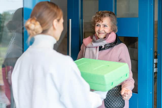 A volunteer delivering a hot meal to door of senior citizen Picture: Adobe. Posed by models