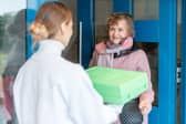 A volunteer delivering a hot meal to door of senior citizen Picture: Adobe. Posed by models
