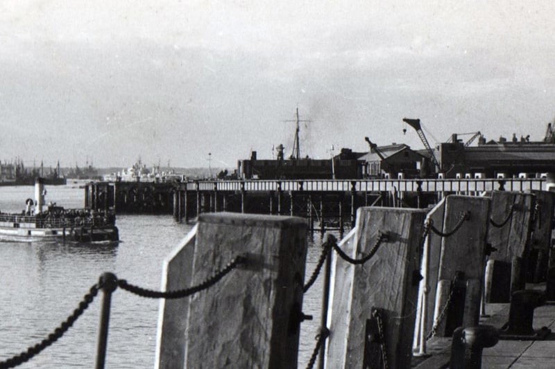 Looking north up the harbour from the Portsmouth Harbour Railway Station landing stage we see from left to right in the distance a paddle steamer at rest and then, closer to camera the Gosport Ferry loaded with sailors perhaps ready to go on week-end leave.