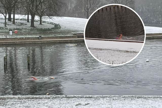 A man in a red swim cap has been captured swimming in a lake during a freezing snow storm.