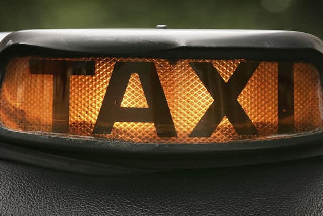 A black taxi cab driver illuminates his taxi sign. Photo by Peter Macdiarmid/Getty Images