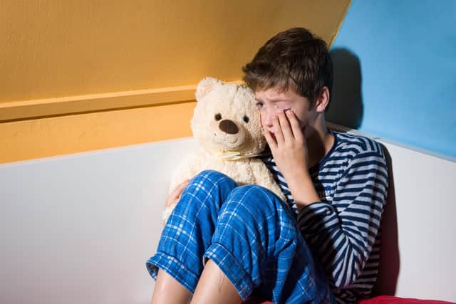 An emotional child cradles a teddy in his bedroom. Photo posed by a model. Picture: Shutterstock