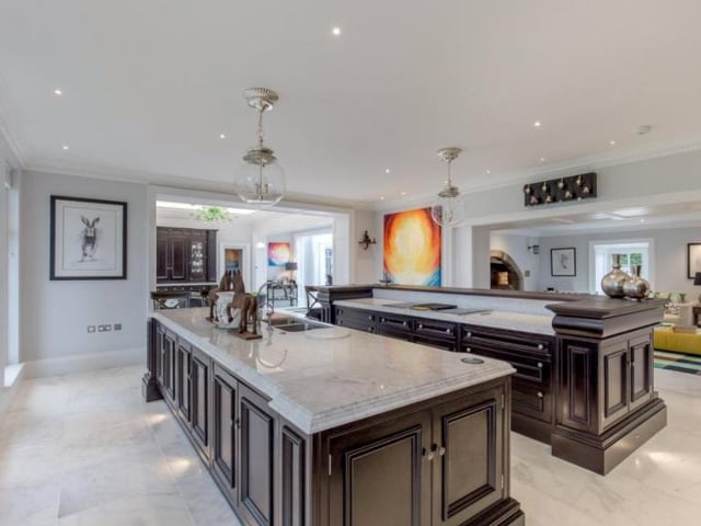 The modern kitchen is described as “the heart of the house”. It was designed by Clive Christian and boasts two island units with white marble work surfaces and Wolf induction hobs.
