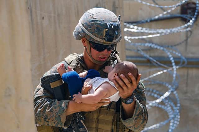 A US Marine comforts a child while they wait for the mother during an evacuation at Hamid Karzai International Airport, Kabul. Picture: Nicholas Guevara/US Marine Corps/AFP via Getty Images.