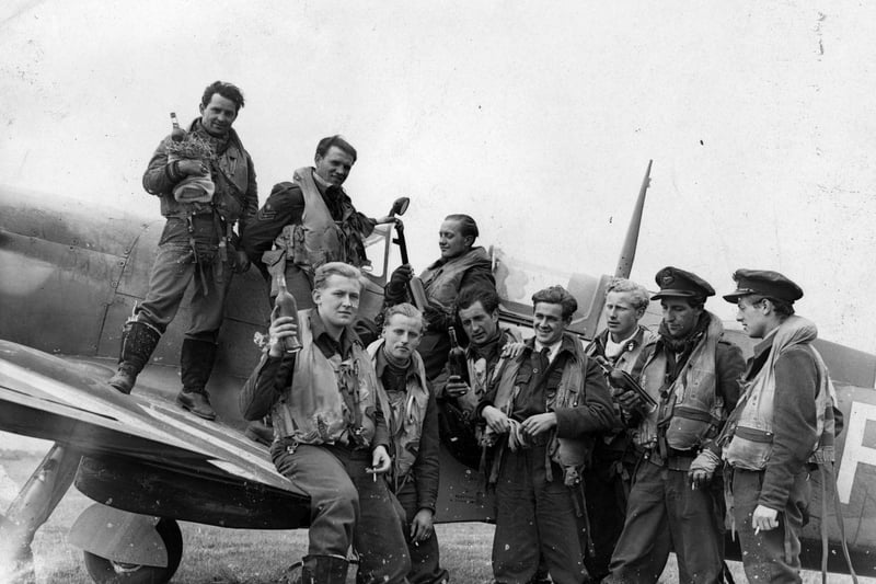 29th June 1944:  Pilots from a Spitfire Squadron, who have returned from a French attack, holding bottles of wine.  (Photo by Harry Shepherd/Fox Photos/Getty Images)
