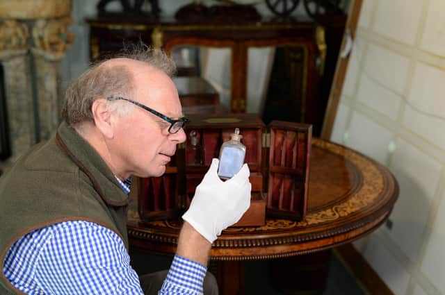 Charles Wallrock inspects one of the bottles in the medicine cabinet that belonged to Sir William Beatty, Nelson's surgeon at Trafalgar.